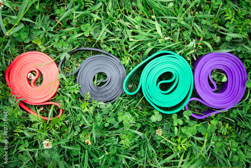 set of colorful elastic fitness bands  on green grass . Outdoor workouts concept