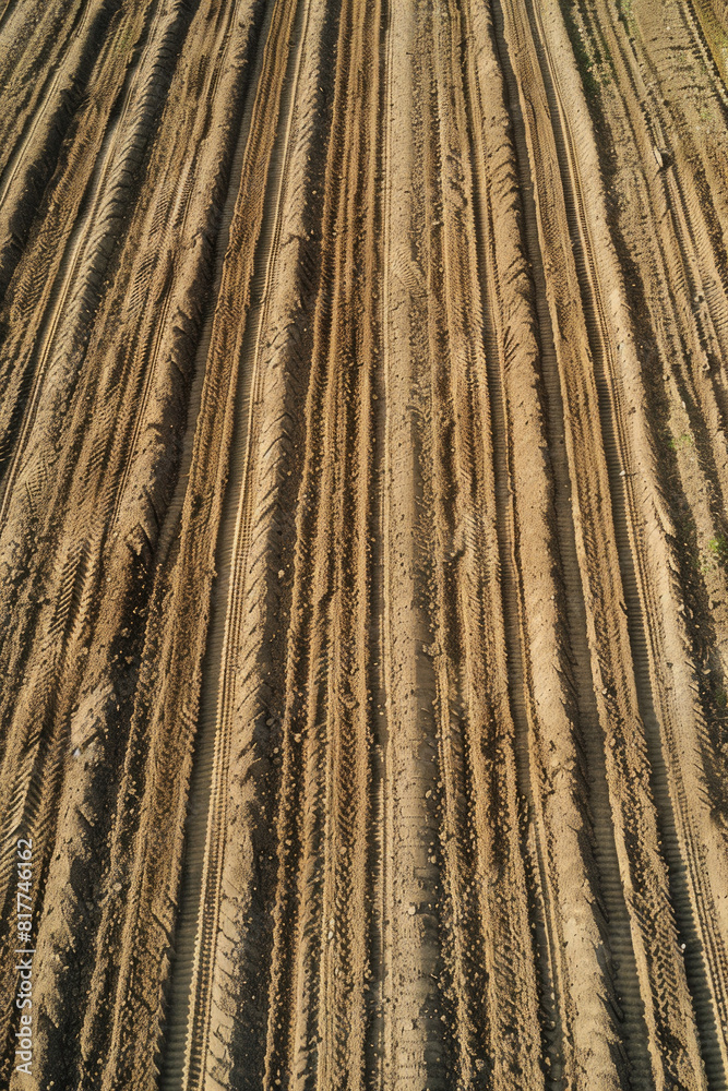 A top-down view of a freshly plowed field, with rows of soil creating a textured pattern. A top-down view of a freshly plowed field, with rows of soil creating a textured pattern.