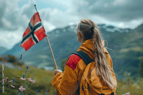 Blond woman with backpack looking at norwegian flag on mountain photo