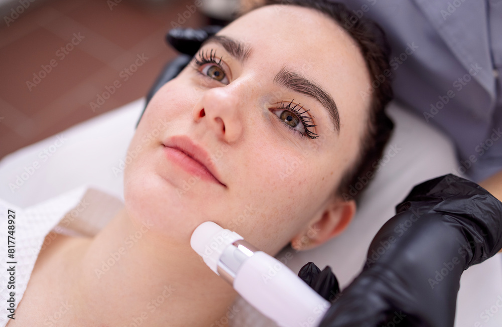 Fototapeta premium Young beautiful woman getting lifting anti-aging, face massage a