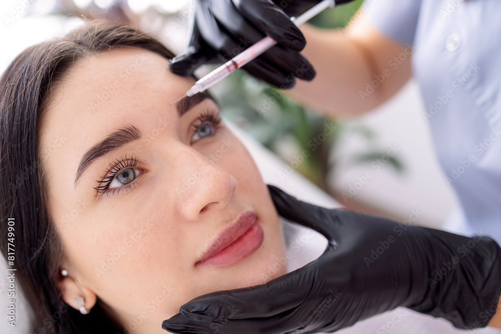 Beauty injections. Female cosmetologist in black gloves makes an injection
