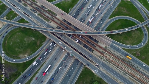 Sprawling highway networks alive with movement, cars navigate concrete sprawl in aerial view. Multi-tiered urban roadways brim with commuters, drone video reveals organized chaos in motion.