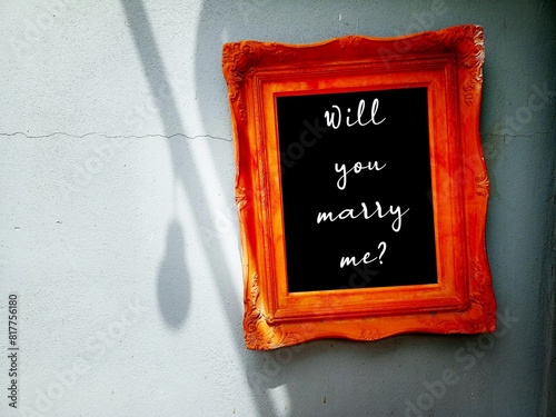 A wood frame on copy space wall with handwritting WILL YOU MARRY ME?  a simple standard marriage proposal when someone pop a question to the one they love