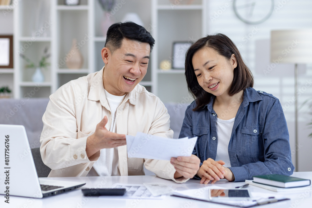 Smiling couple discussing their financial planning at home, sitting at a table with a laptop and paperwork. Concept of family budgeting, financial management, and teamwork. Smiling couple discussing their financial planning at home, sitting at a table with a laptop and paperwork. Concept of family budgeting, financial management, and teamwork.