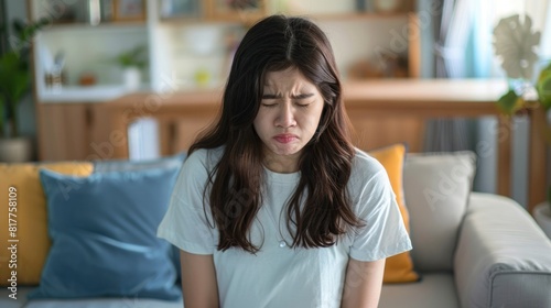 Free Download Asian woman grimacing in pain, sitting on sofa - GFXLoad