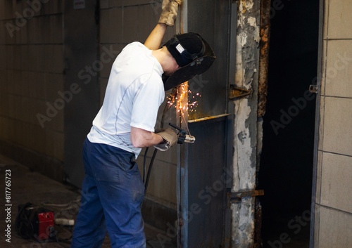 Arc Welding Door Jam. Welder repairing a garage door. Selective focus of welder repairing an iron door.