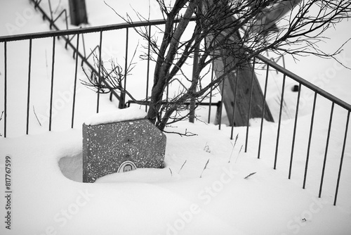 A grave covered with snow in an old cemetery in the Far North of Russia in the Arctic. Headstone and fence in the snow. Memories and sad mood. Black and white photography.