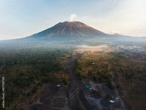 Фотография A tranquil scene of a majestic volcano seen from above, with a plume of smoke gently rising from the crater