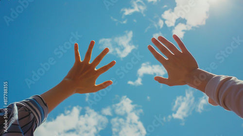 Two hands of two people with the blue sky in the background