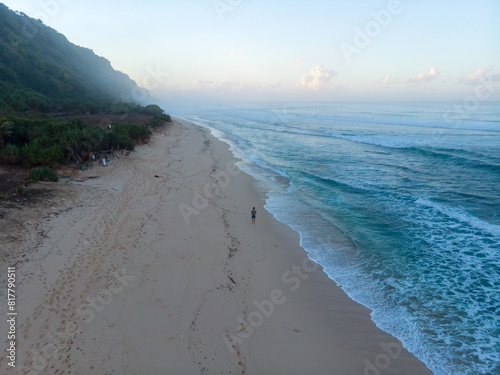 Принти на полотні A lone person walking on a tranquil beach at dawn with gentle ocean waves and a