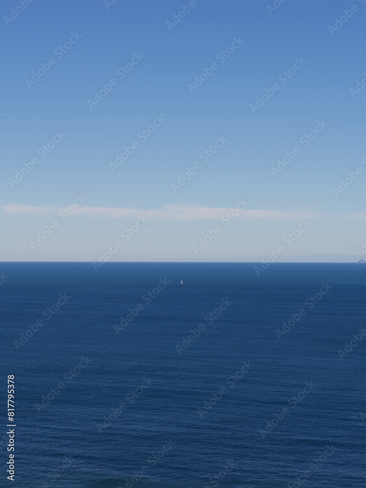 Scenic view of a sailboat sailing through the blue sea Scenic view of a sailboat sailing through the blue sea
