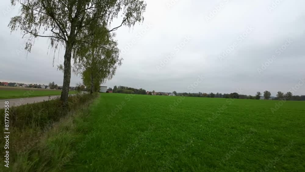 Drone shot of a narrow trail passing through green grassy fields in the countryside on a cloudy day Drone shot of a narrow trail passing through green grassy fields in the countryside on a cloudy day