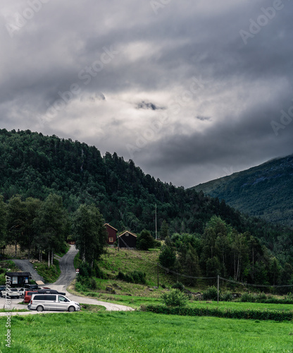 Cars parked at Innerdalen national park parking lot with the Trollheimen mountain range covered in white clouds on an overcast afternoon. Møre og Romsdal in Norway