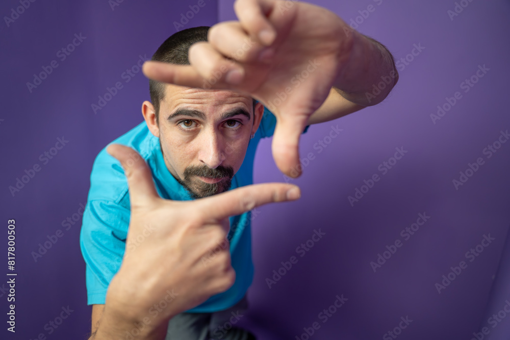Man doing frame using hands and fingers, isolated over purple background. High quality photo