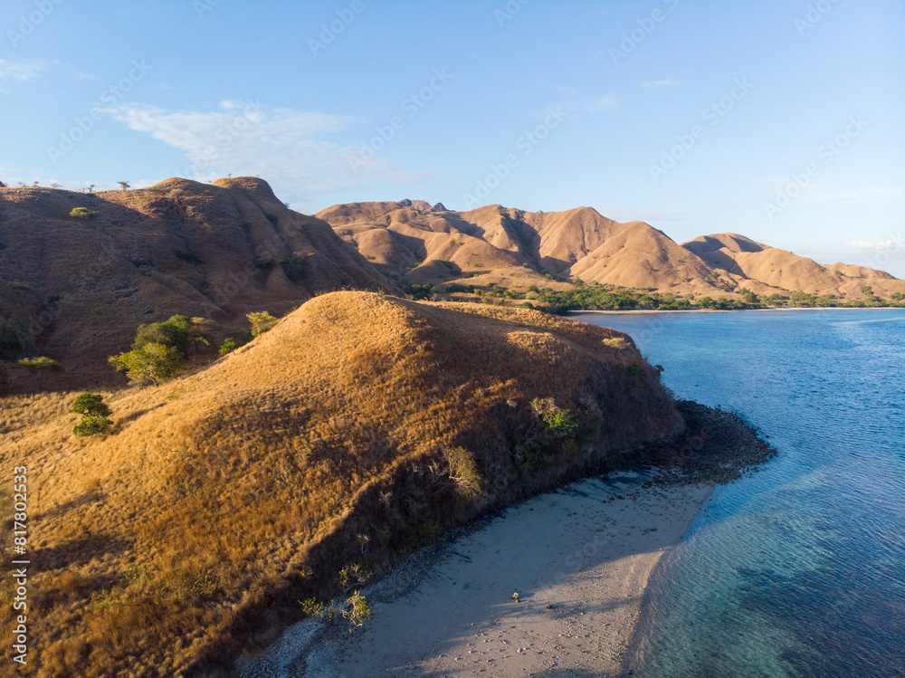 Obraz premium A serene coastal landscape with dry hills and a clear blue sky