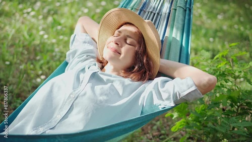 A young Caucasian woman in a hat chilling in a hammock in the spring garden