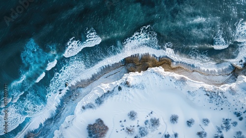 An aerial perspective of a frozen snowy cliff meeting the azure waters of the ocean, showcasing the beauty of this natural geological phenomenon AIG50