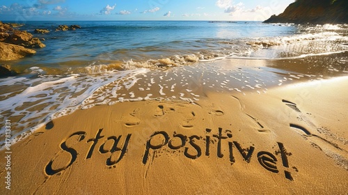 A picturesque beach scene with "Stay positive!" carved in large letters into the golden sand, waves gently lapping nearby