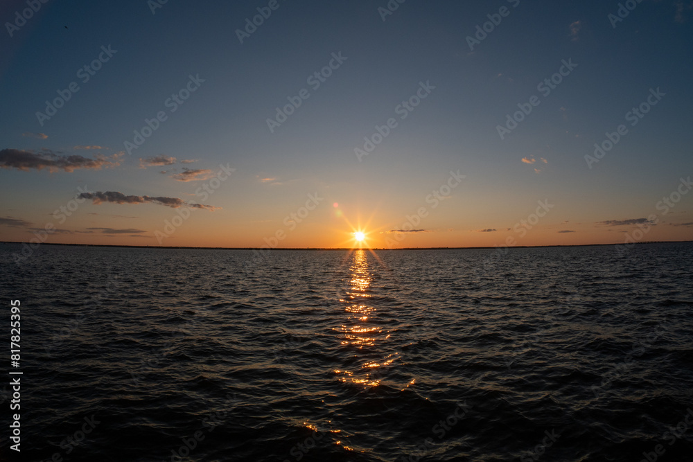 a sunset reflects in the surface of the water, with the sun setting on top a sunset reflects in the surface of the water, with the sun setting on top