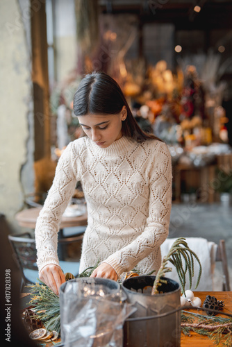 A beautiful young woman engrossed in a Christmas decor crafting workshop.