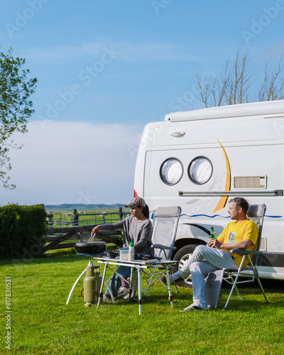 Two individuals are seated in front of their RV, enjoying the peaceful surroundings of a grassy field in Texel, Netherlands. camping at a farm in Texel Netherlands