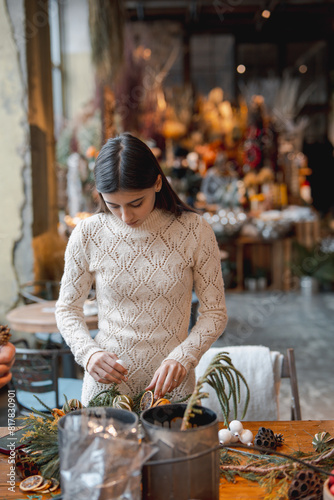 A young woman crafting a Christmas wreath at a holiday decor workshop.