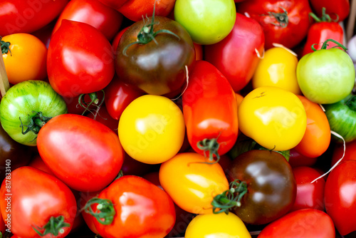 a bunch of multicolored tomatoes piled together with green, red and yellow