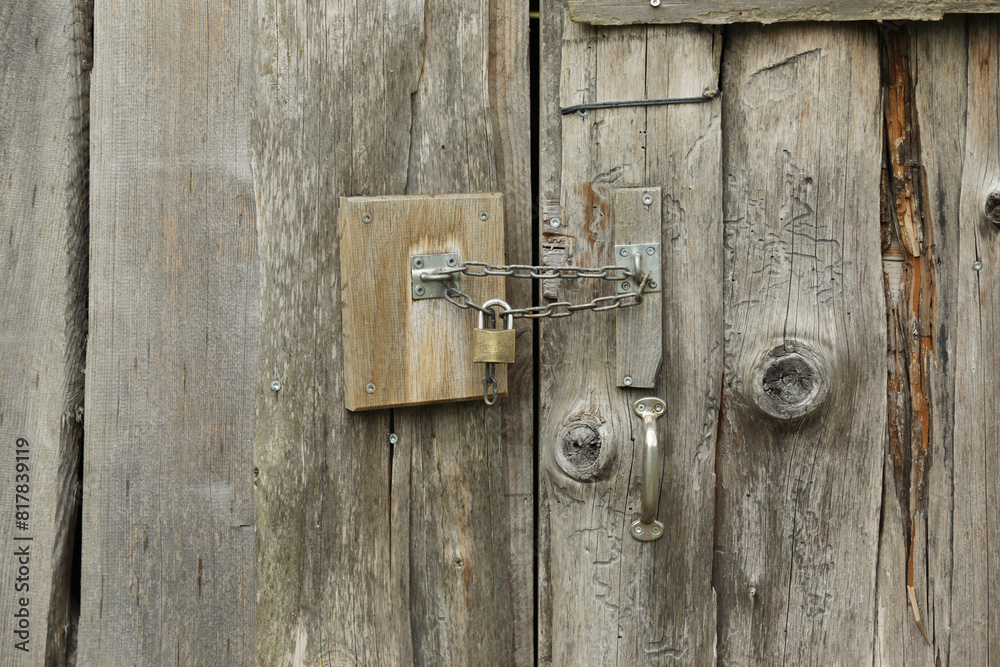 Old wooden doors in a barn with a small lock on a chain Old wooden doors in a barn with a small lock on a chain