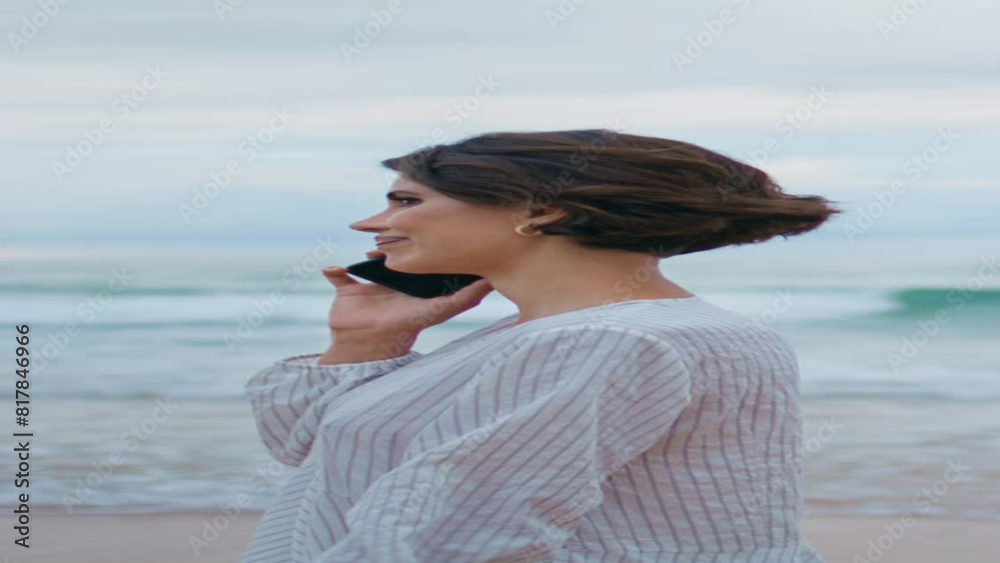Woman enjoying cellphone conversation at ocean waves vertical. Model stepping Woman enjoying cellphone conversation at ocean waves vertical. Model stepping