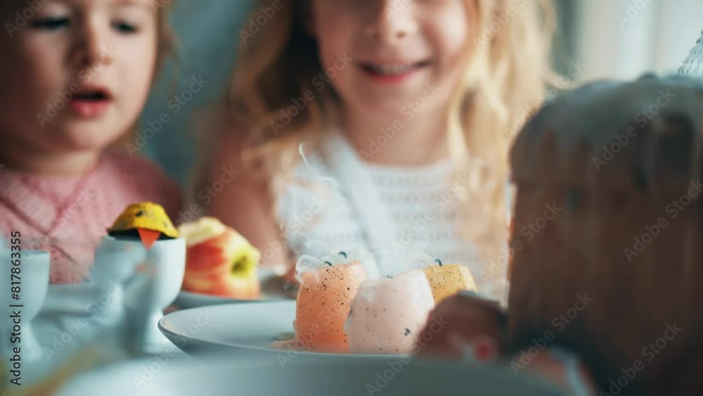 Little girls blow out egg candles at the decorated Easter table at home