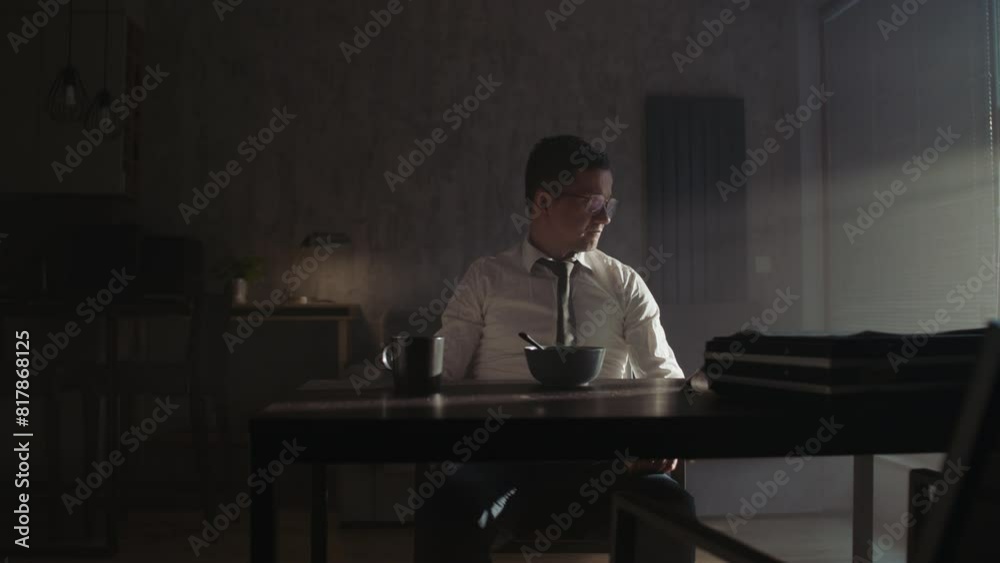 A sad man in a white shirt eats cereal for breakfast A sad man in a white shirt eats cereal for breakfast