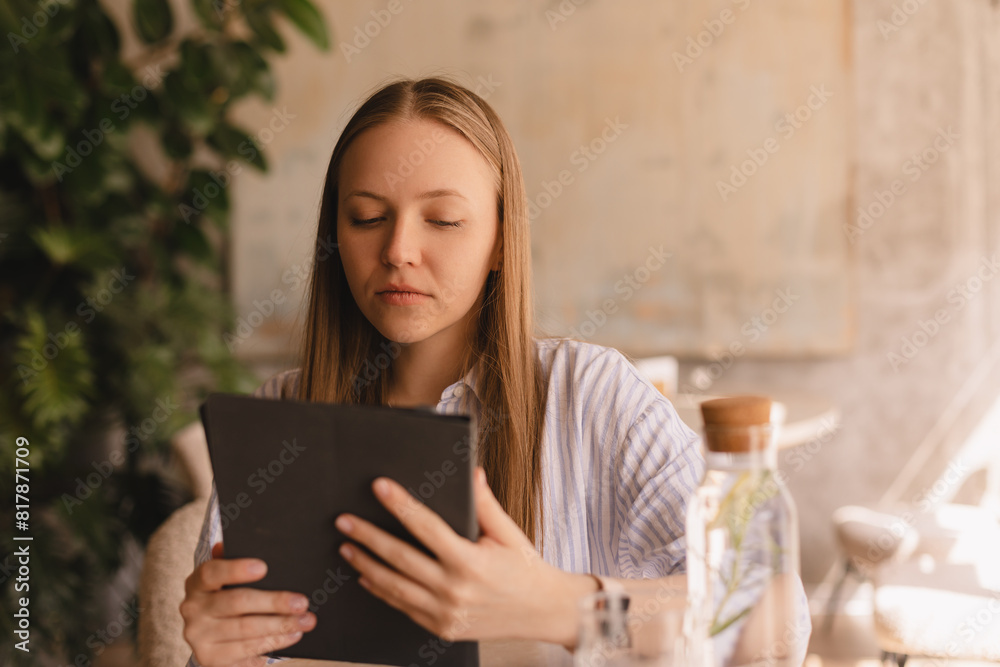 Young smart busy professional business woman executive, female company worker or manager holding digital tablet using pad technology device working sitting in cafe. Young smart busy professional business woman executive, female company worker or manager holding digital tablet using pad technology device working sitting in cafe.
