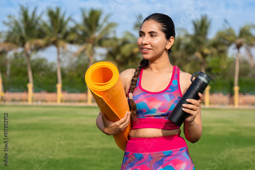 young indian fitness woman with yoga mat, bottle & shaker. exercise, meditation, workout, outdoor, mental health.