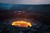 A drone hovers above a glowing, active volcano crater, capturing footage of the flowing molten lava, in a dramatic, volcanic landscape during dusk.