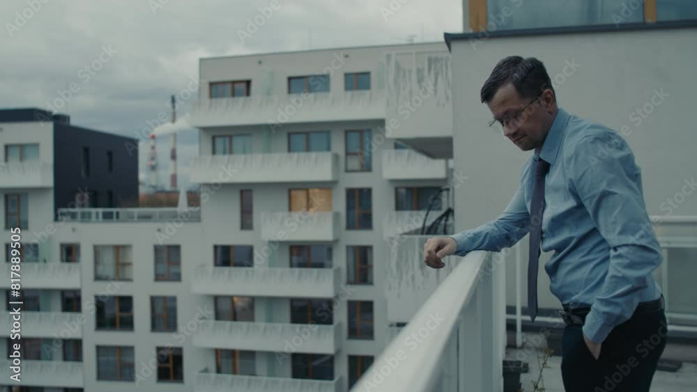 A sad middle-aged manager in a blue shirt lights a cigarette on a terrace A sad middle-aged manager in a blue shirt lights a cigarette on a terrace