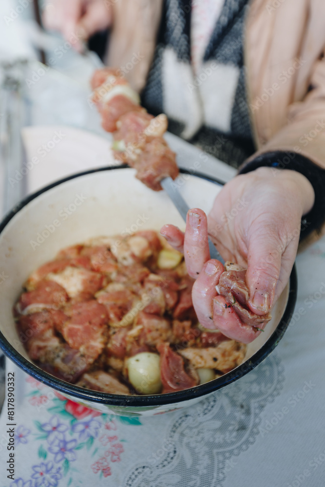 woman hands and marinated pork shashlik on skewers
