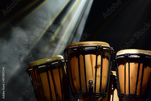 Three conga drums on a dimly lit stage, illuminated by a spotlight with visible smoke in the background.