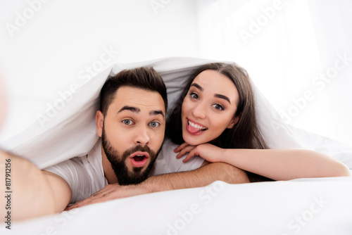 Photo of carefree funky couple wear white t-shirts recording video stick out indoors apartment bedroom