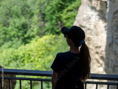 Young girl enjoying beauty of nature looking at mountain from a viewpoint close to rocks
