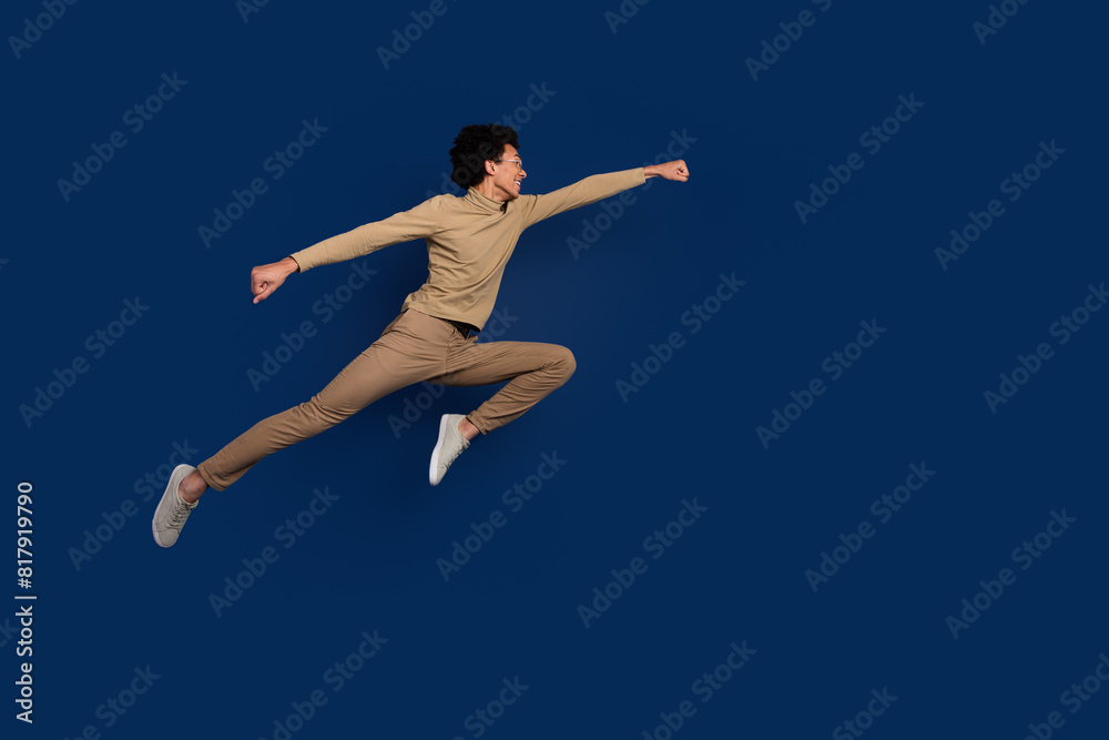 Full body photo of attractive young man jump fly superman dressed stylish beige clothes isolated on dark blue color background