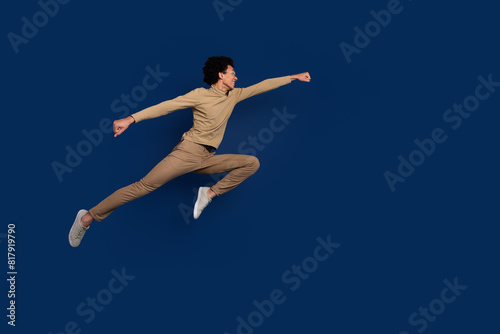 Full body photo of attractive young man jump fly superman dressed stylish beige clothes isolated on dark blue color background