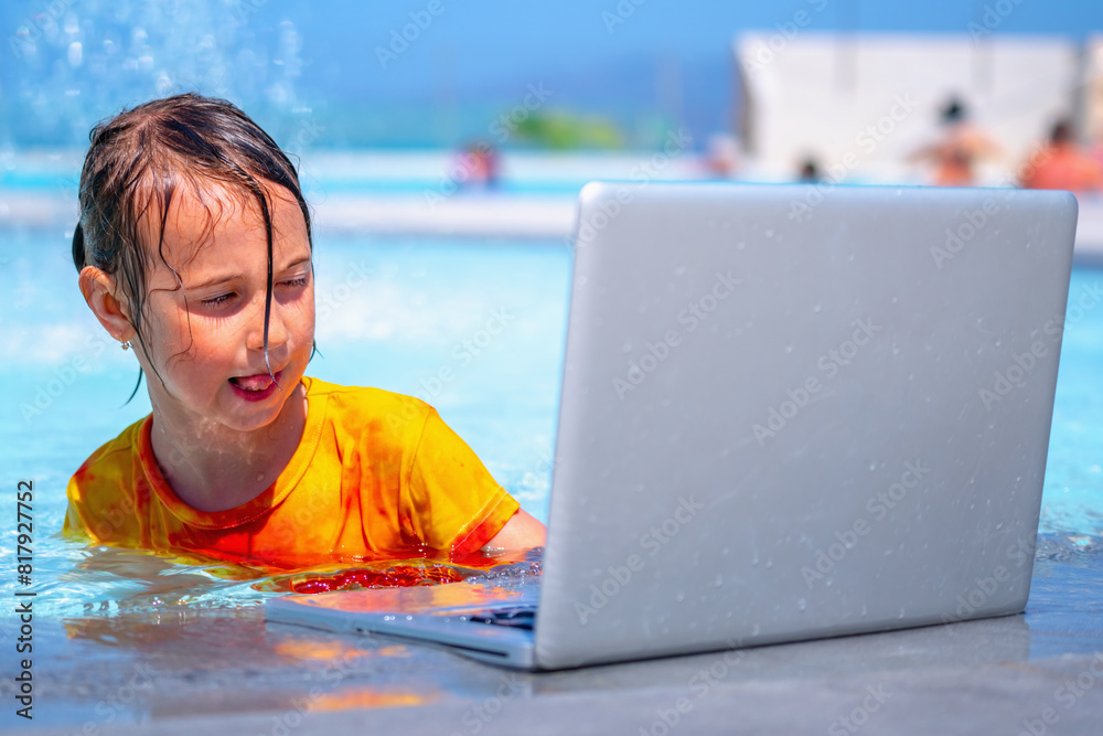 A perfect vacation: sea, swimpool and laptop. Portrait of young girl relaxing in the pool at luxury hotel with laptop against ocean background. Travel, holiday and summer concept. Horizontal image.