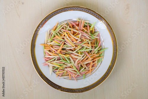 Uncooked Semai pitha or Chui pitha on a white plate on a wooden background. It is a traditional Bangladeshi sweet dish, also called Chutki pitha. Top view.  photo