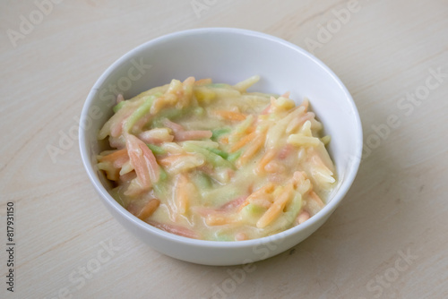 Delicious Semai pitha or Chui pitha on a white bowl on a wooden background. It is a traditional Bangladeshi sweet dish, also called Chutki pitha. 