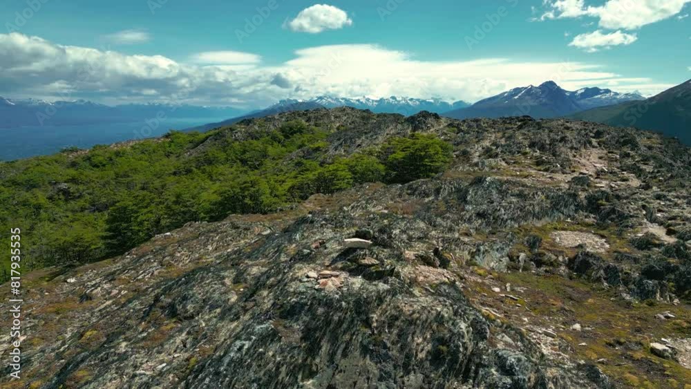 A couple woman and man stand on mountain peak overlooking the Beagle Channel at windy day in Ushuaia, Tierra del Fuego, Argentina. Aerial drone video. A couple woman and man stand on mountain peak overlooking the Beagle Channel at windy day in Ushuaia, Tierra del Fuego, Argentina. Aerial drone video.