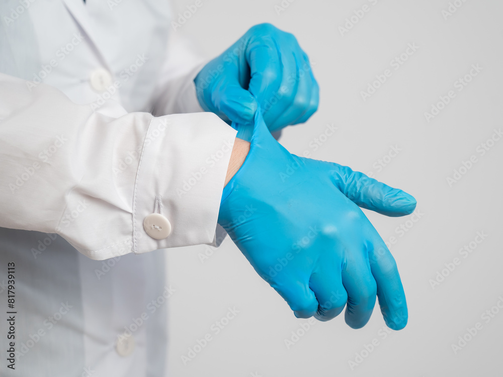 The doctor puts on latex gloves on a white background. The doctor puts on latex gloves on a white background.
