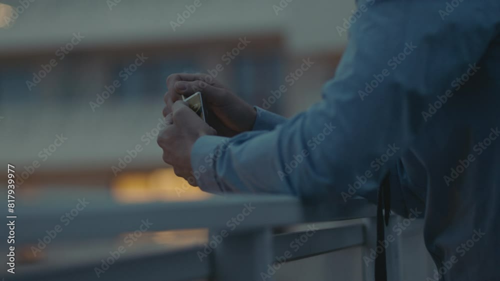 A sad middle-aged man in a blue shirt lights matches on the terrace A sad middle-aged man in a blue shirt lights matches on the terrace
