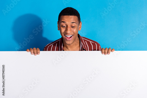 Portrait of impressed man dressed striped shirt over white t-shirt look at discount on empty space isolated on blue color background