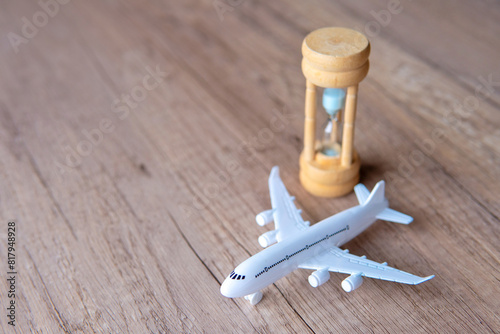 Toy airplane on a wooden table next to a hourglass. Copy space. Flight delay, waiting concept. photo