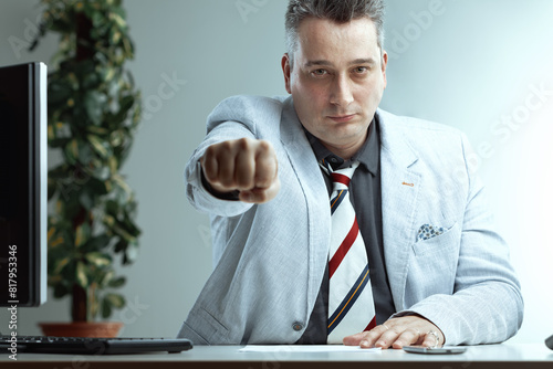 Determined man extends fist, office background visible photo